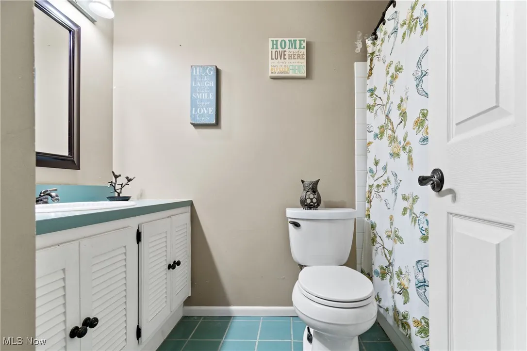 Bathroom with vanity, dark tile patterned floors, and curtained shower