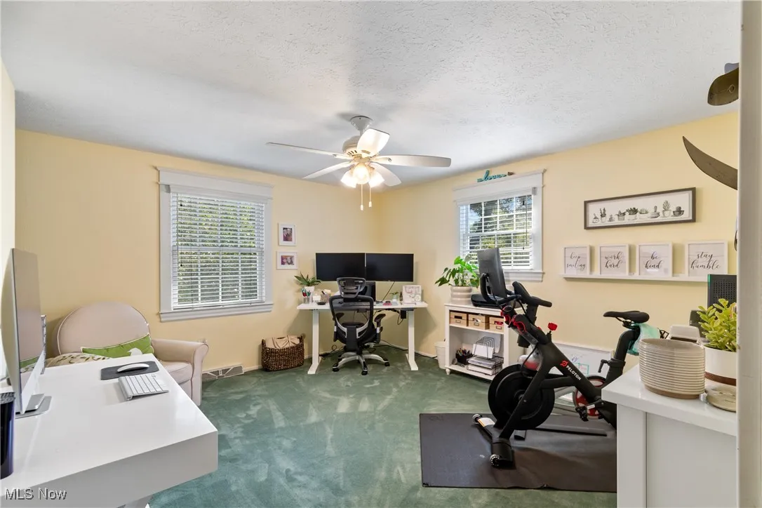 Office with dark carpet, a textured ceiling, and ceiling fan