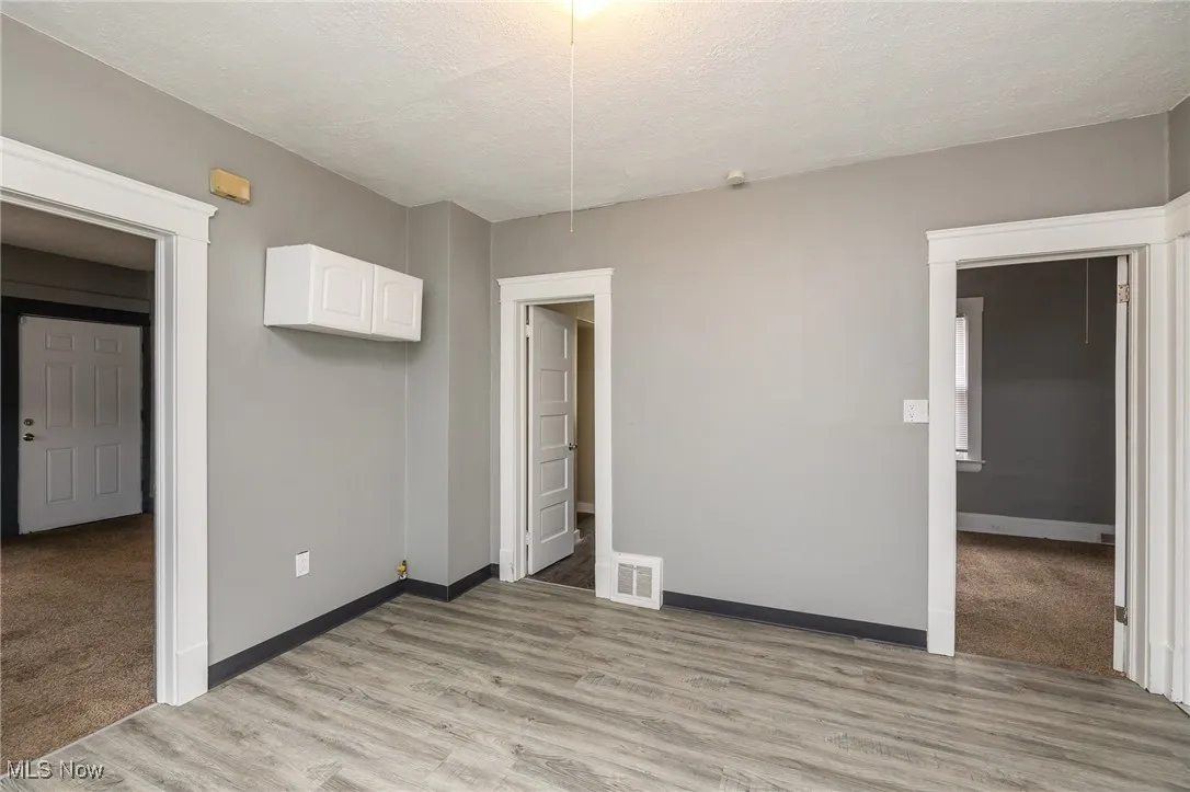 Unfurnished room with a textured ceiling and light wood-style floors