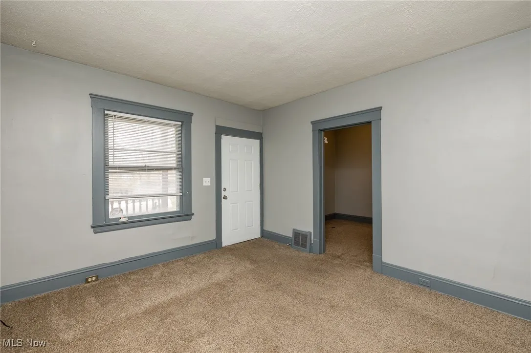Carpeted empty room featuring a textured ceiling and baseboards