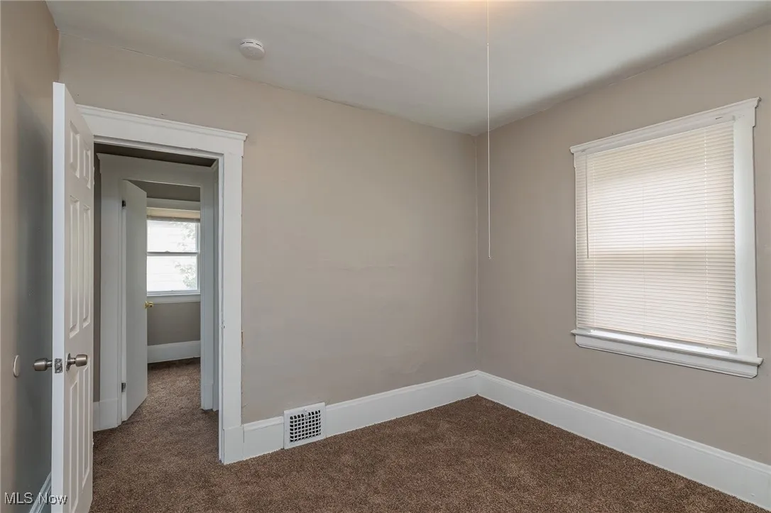 Spare room with dark carpet and baseboards