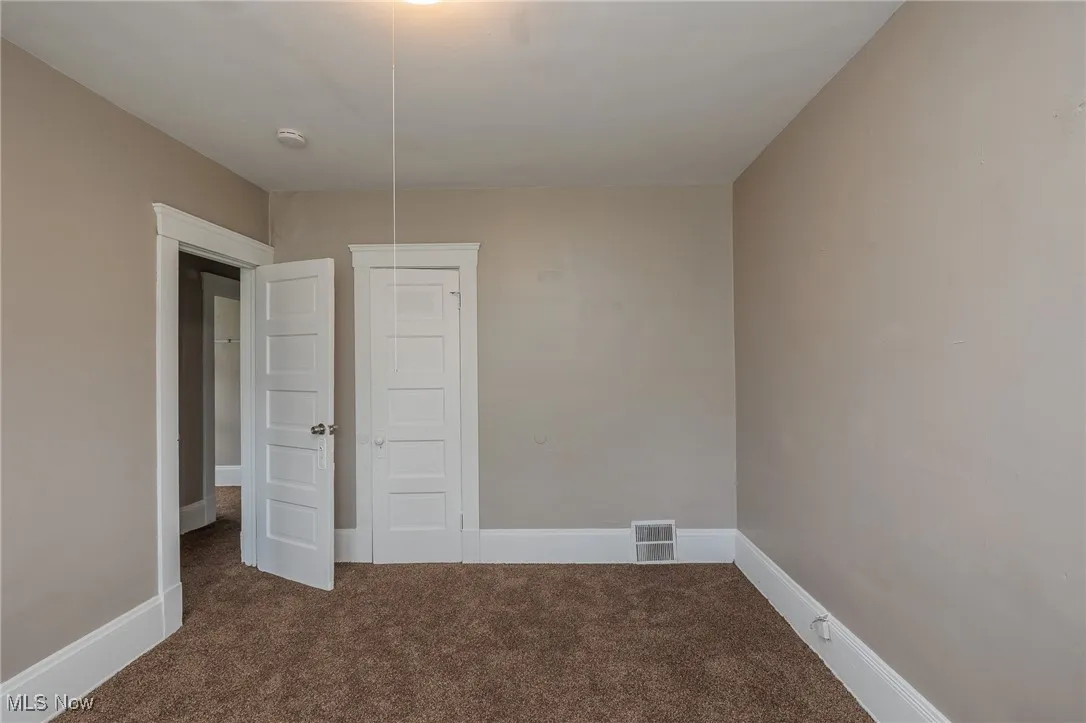 Empty room featuring dark colored carpet and baseboards