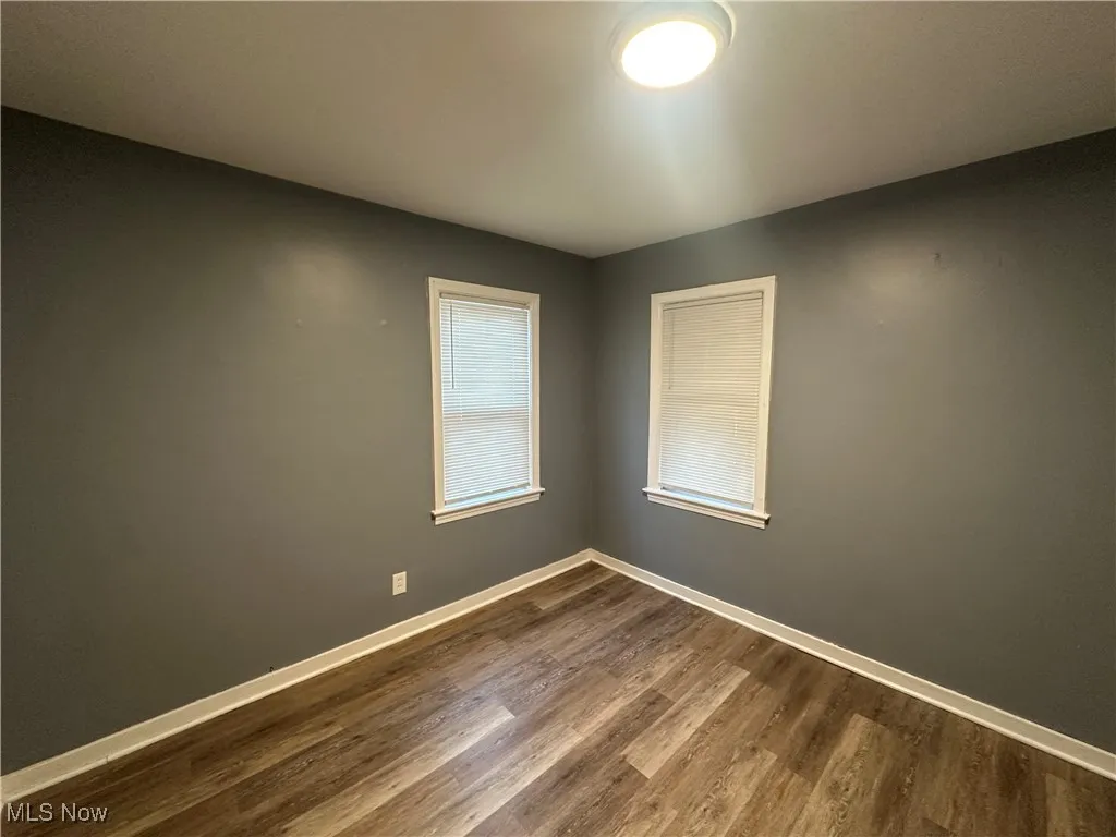 Spare room featuring baseboards and dark wood-style flooring
