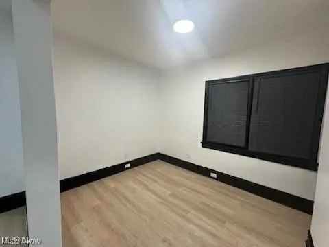 Empty room featuring baseboards and light wood finished floors