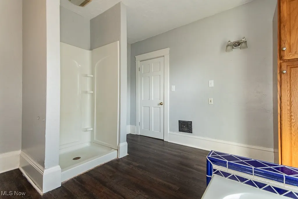 Bathroom featuring a shower stall and dark wood-style floors