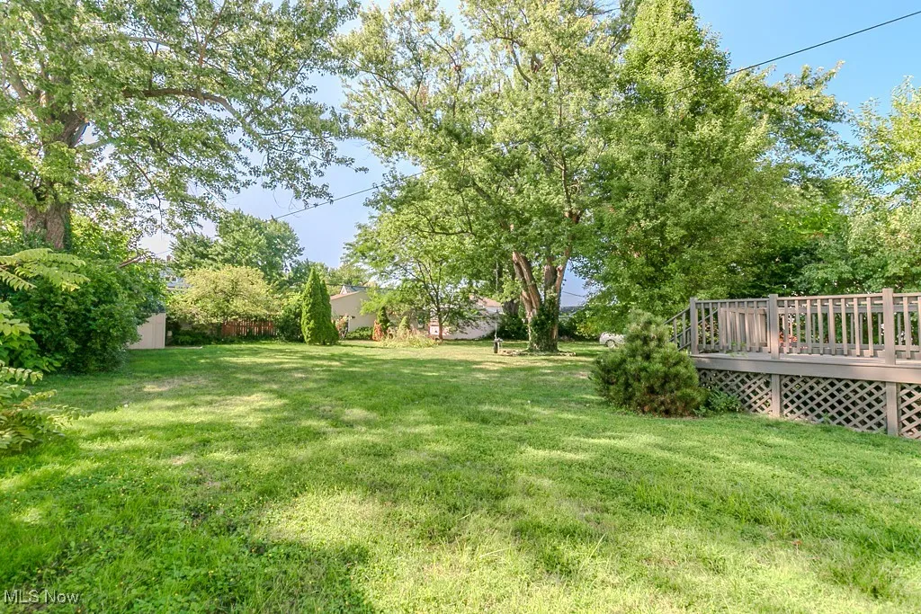 View of green lawn with a wooden deck and a storage unit