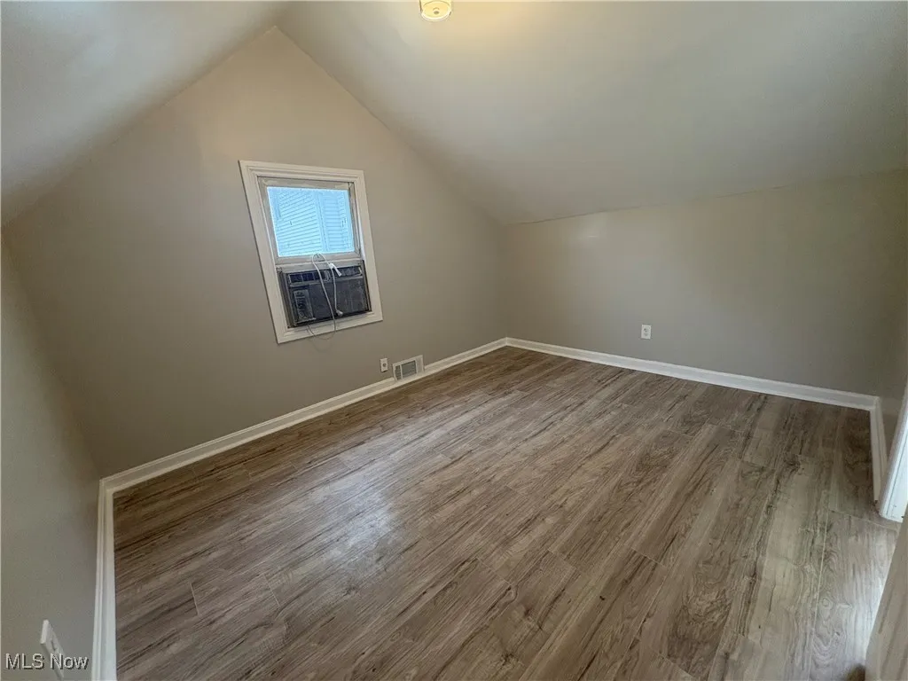 Additional living space with light wood finished floors and vaulted ceiling
