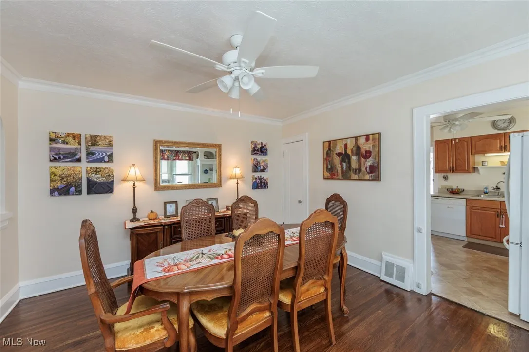 Dining room with dark wood finished floors, ornamental molding, a ceiling fan, and a textured ceiling