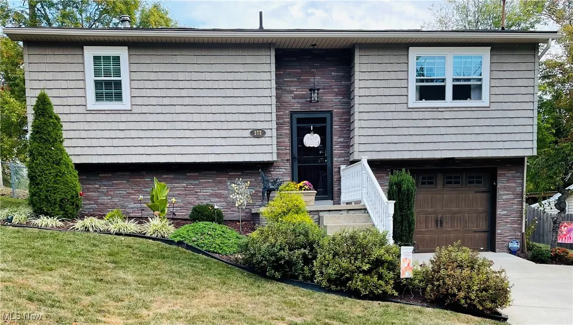 Raised ranch with an attached garage, driveway, and a front yard