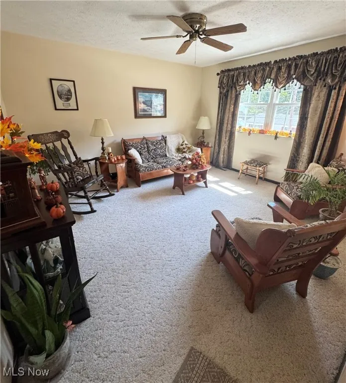 Carpeted living room with a textured ceiling and ceiling fan