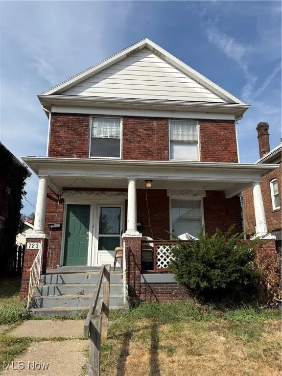 View of front of house with a porch and brick siding