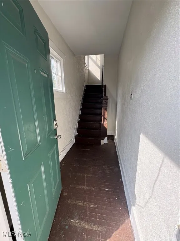 Stairway featuring a textured wall and baseboards