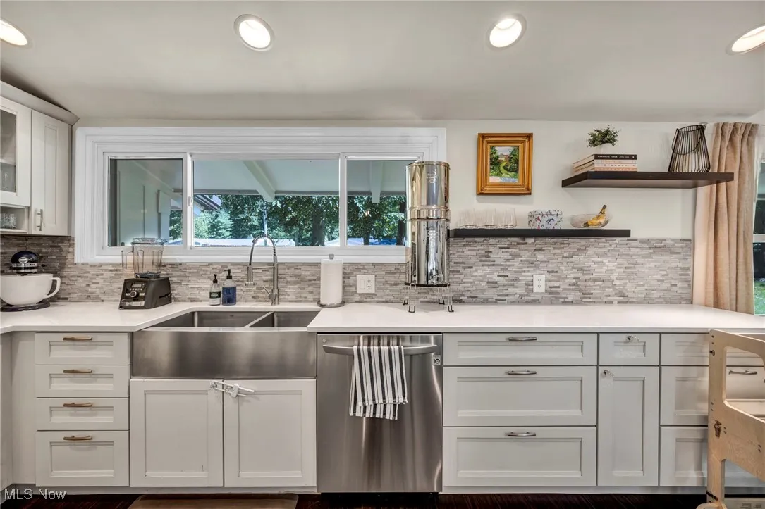 Kitchen featuring white cabinets, recessed lighting, dishwasher, light stone countertops, and glass insert cabinets