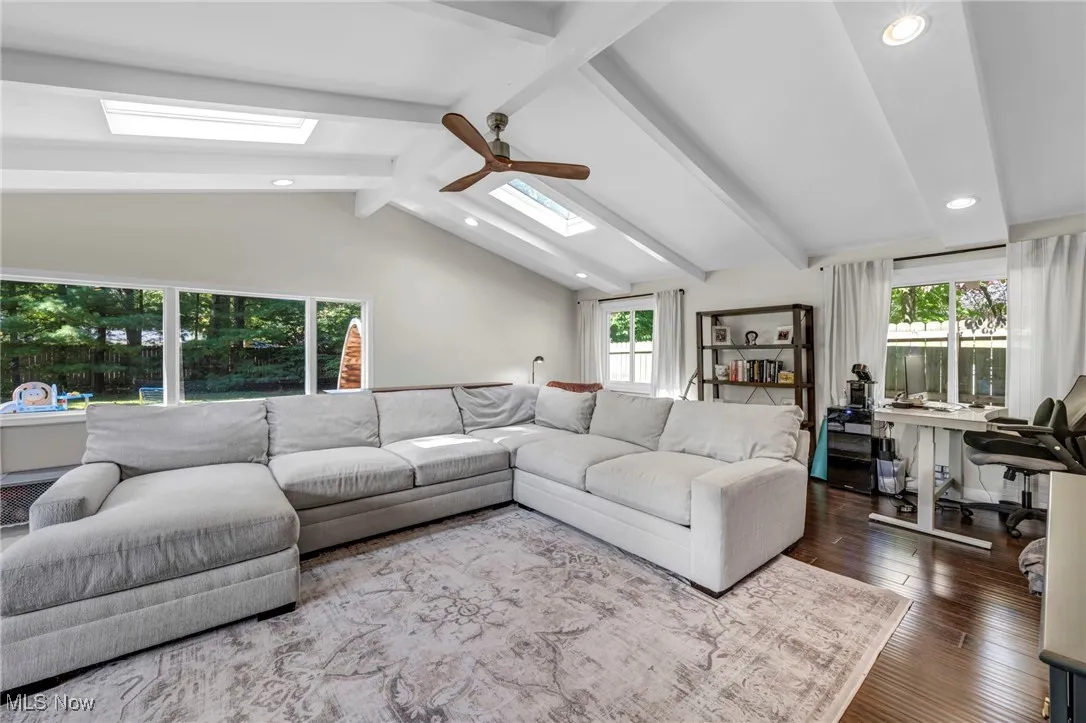 Living room with a desk, a skylight, recessed lighting, a ceiling fan, and wood finished floors