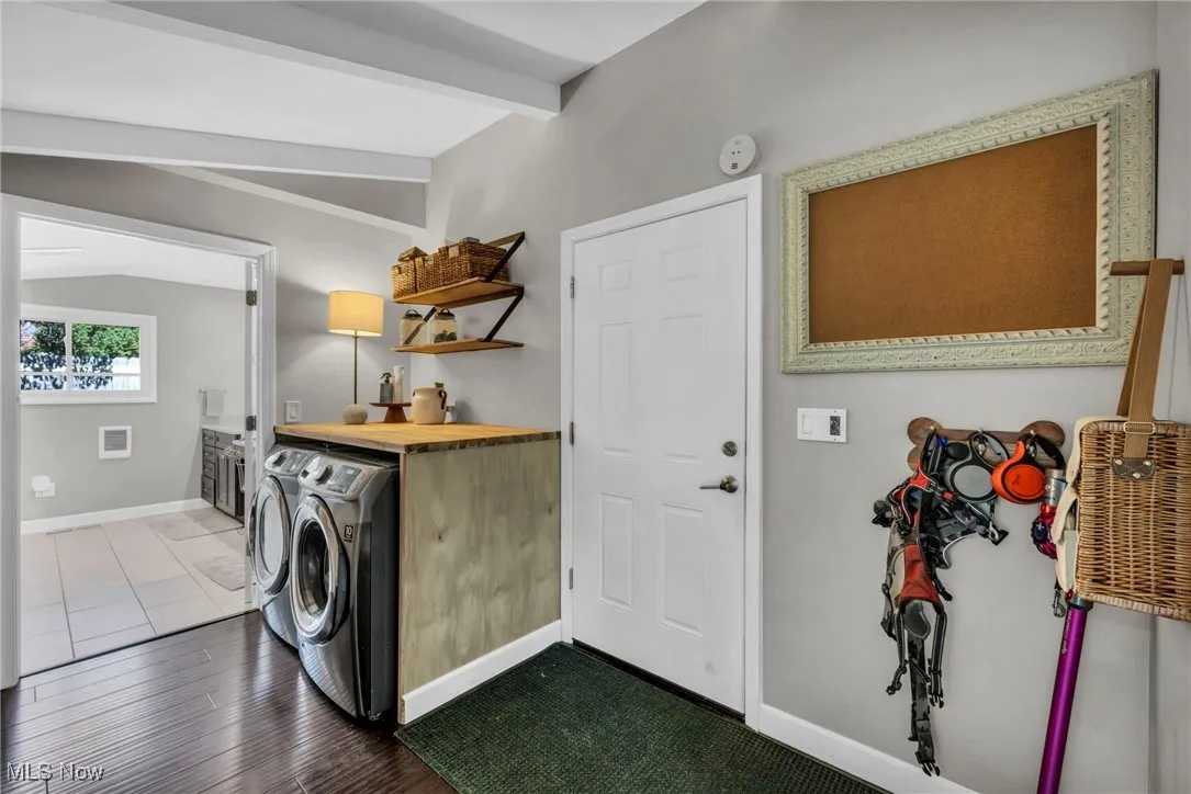 Laundry area with independent washer and dryer and dark wood-type flooring