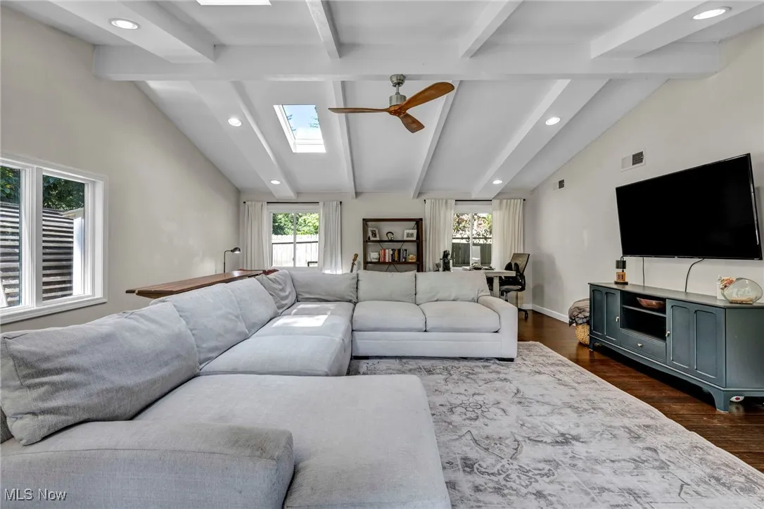 Living room with dark wood-style floors, recessed lighting, a ceiling fan, and a skylight