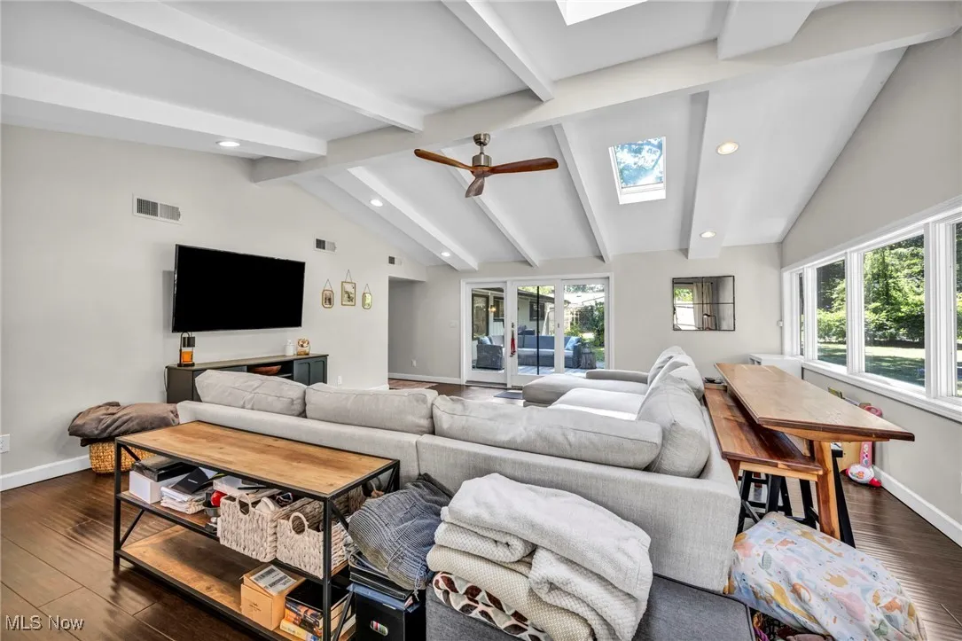 Living room with dark wood-style flooring, healthy amount of natural light, a ceiling fan, a skylight, and recessed lighting