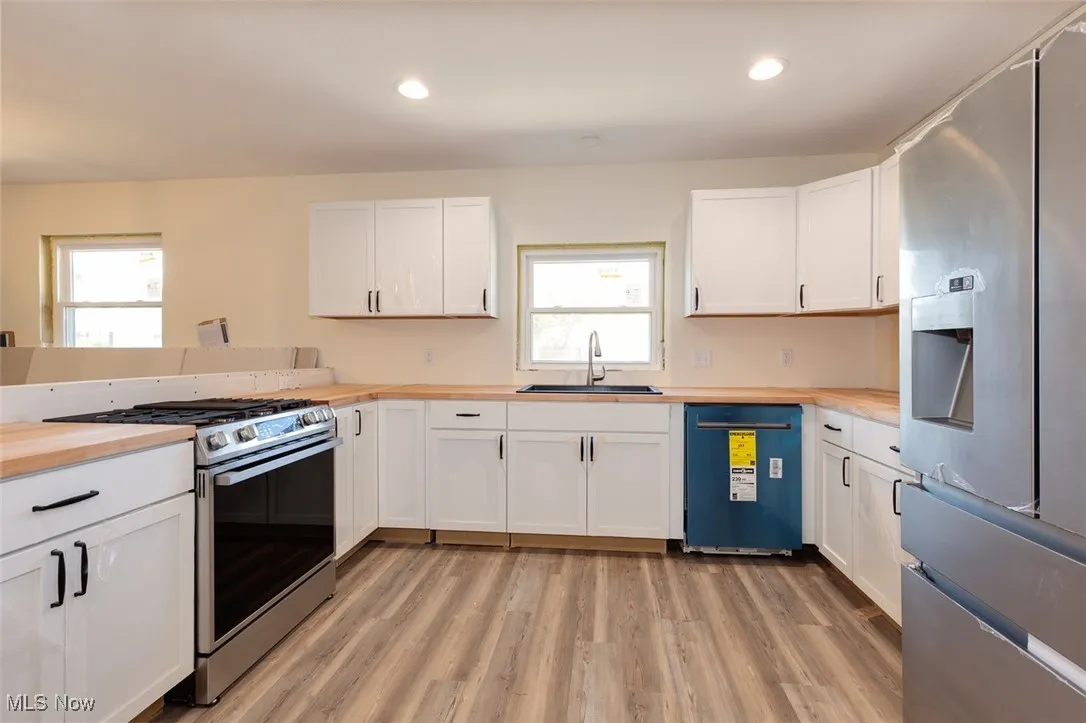 Kitchen featuring appliances with stainless steel finishes, wood counters, white cabinetry, and recessed lighting