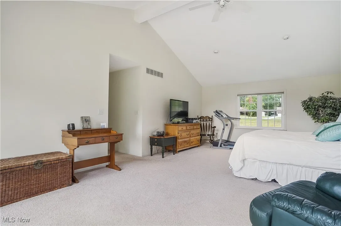 Carpeted bedroom with beamed ceiling, high vaulted ceiling, and a ceiling fan