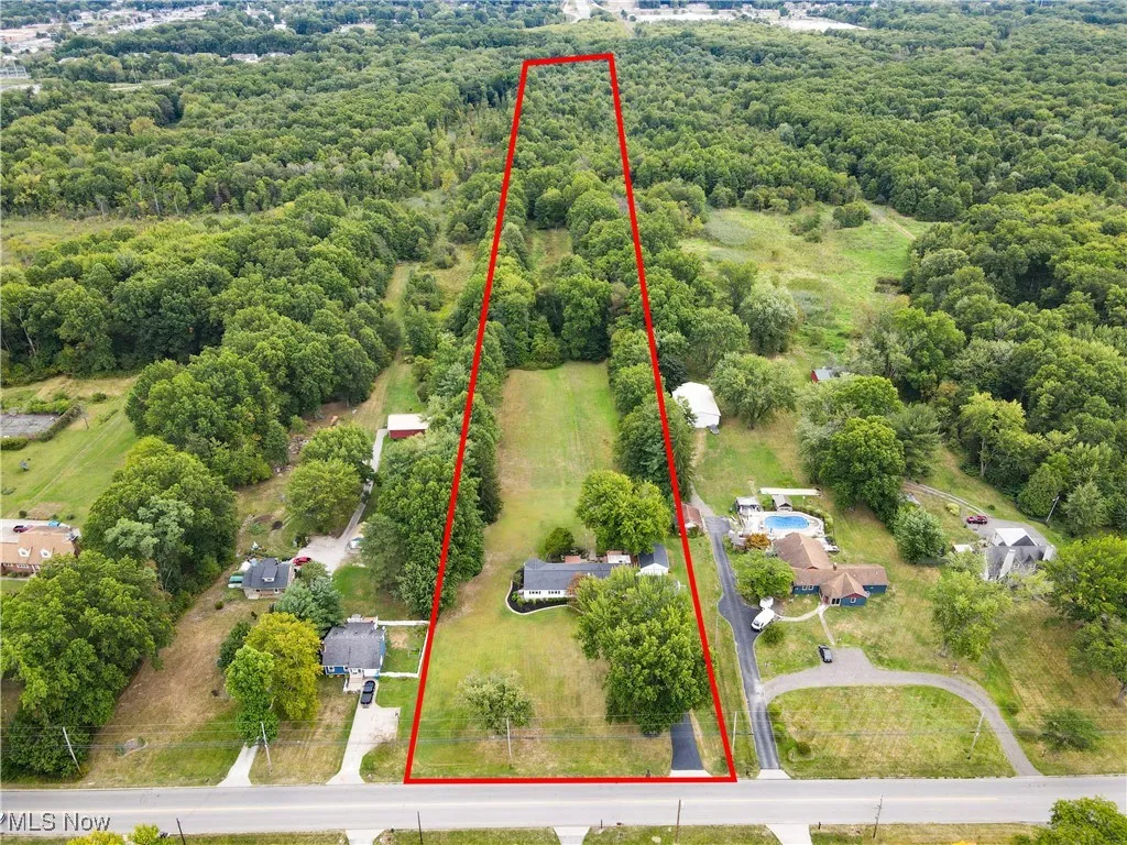 Aerial overview of property's location with property boundaries highlighted and a heavily wooded area