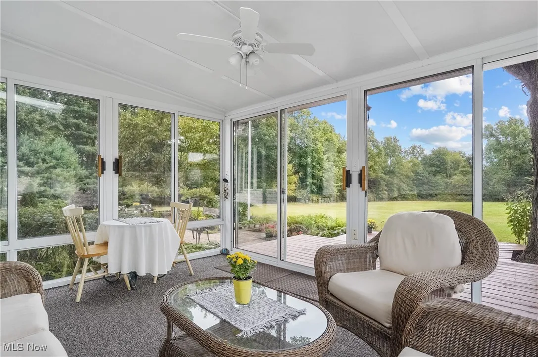 Sunroom featuring ceiling fan, view of wooded area, vaulted ceiling, and french doors