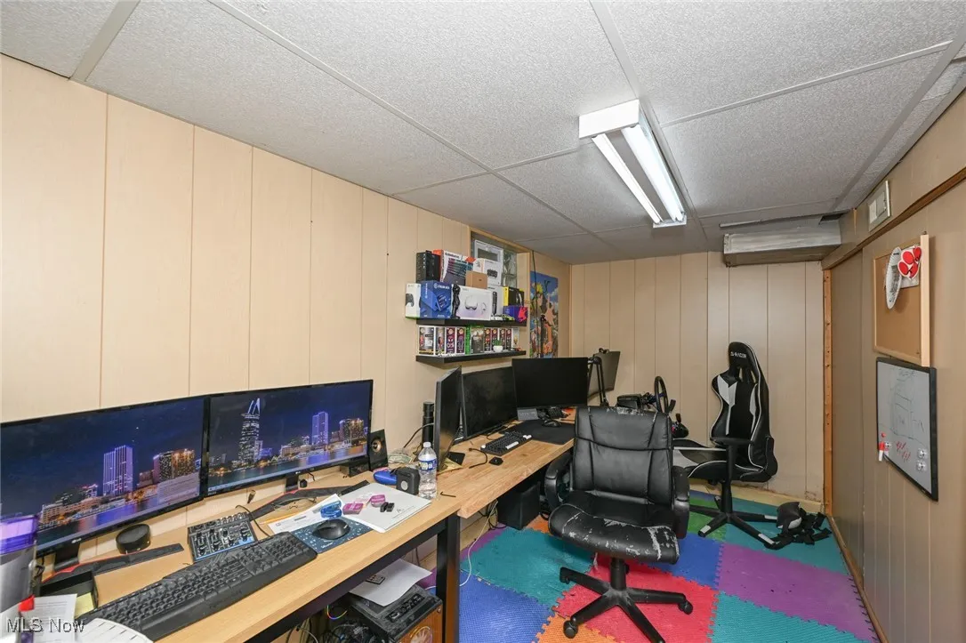 Office space featuring a paneled ceiling, wood walls, and a decorative wall