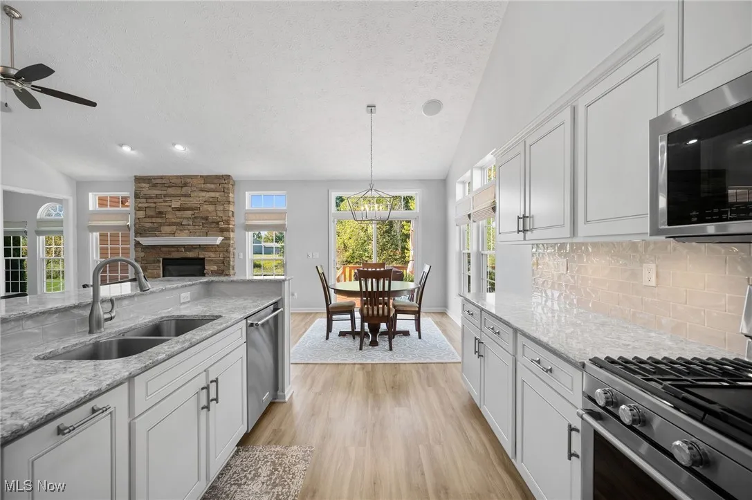 White kitchen cabinets, Cambria quartz countertops, and tile backsplash with stainless steel appliances