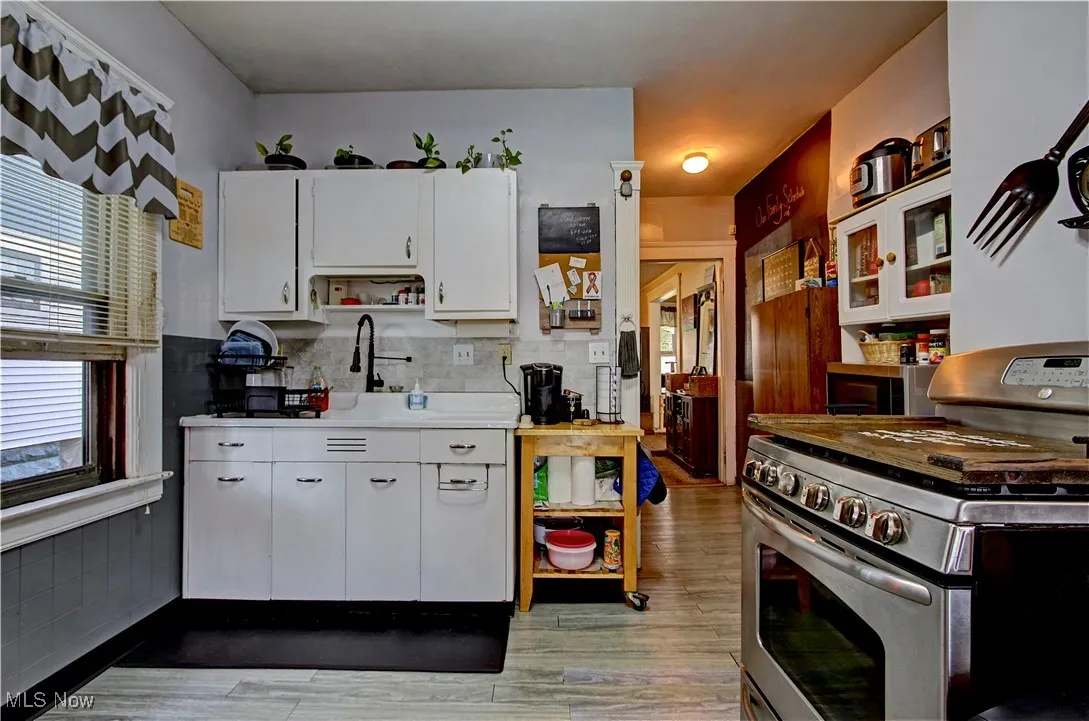 Kitchen featuring appliances with stainless steel finishes, light countertops, white cabinets, and light wood-style flooring