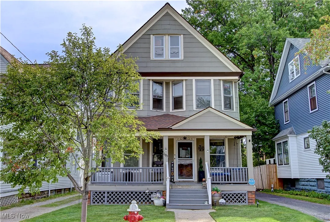View of front of property featuring covered porch, a front yard, and roof with shingles