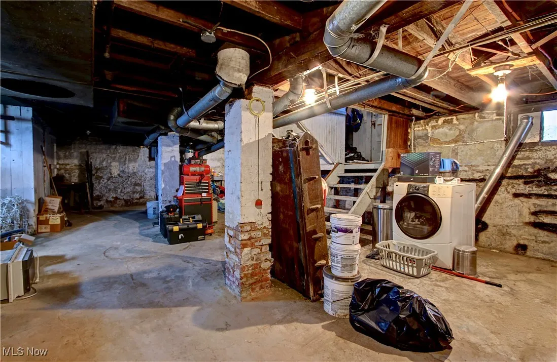 Unfinished below grade area featuring washer / dryer and stairs