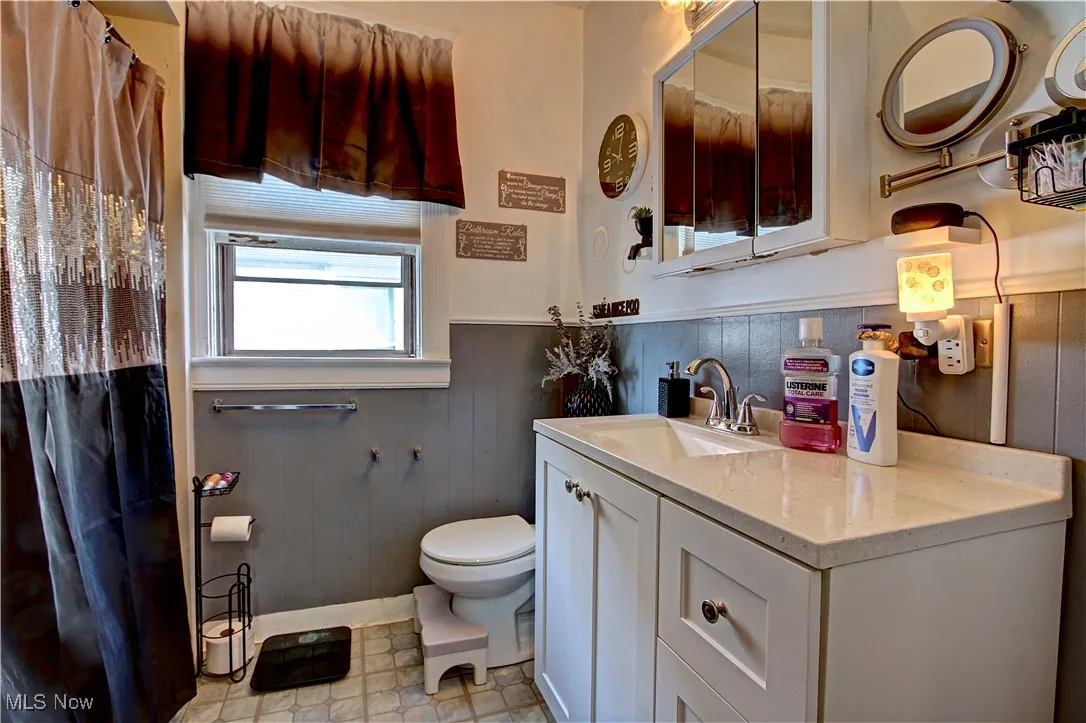Bathroom featuring a wainscoted wall, wood walls, vanity, and a shower with shower curtain