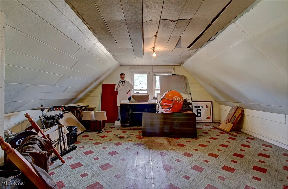 Bonus room featuring lofted ceiling, wooden walls, and light colored carpet