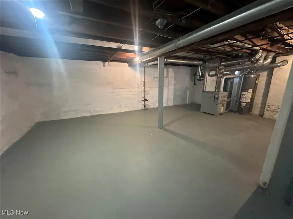Unfinished basement featuring heating unit and water heater