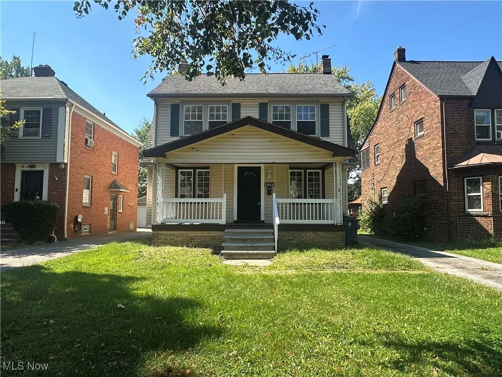 View of front of house with a front yard, covered porch, and a chimney