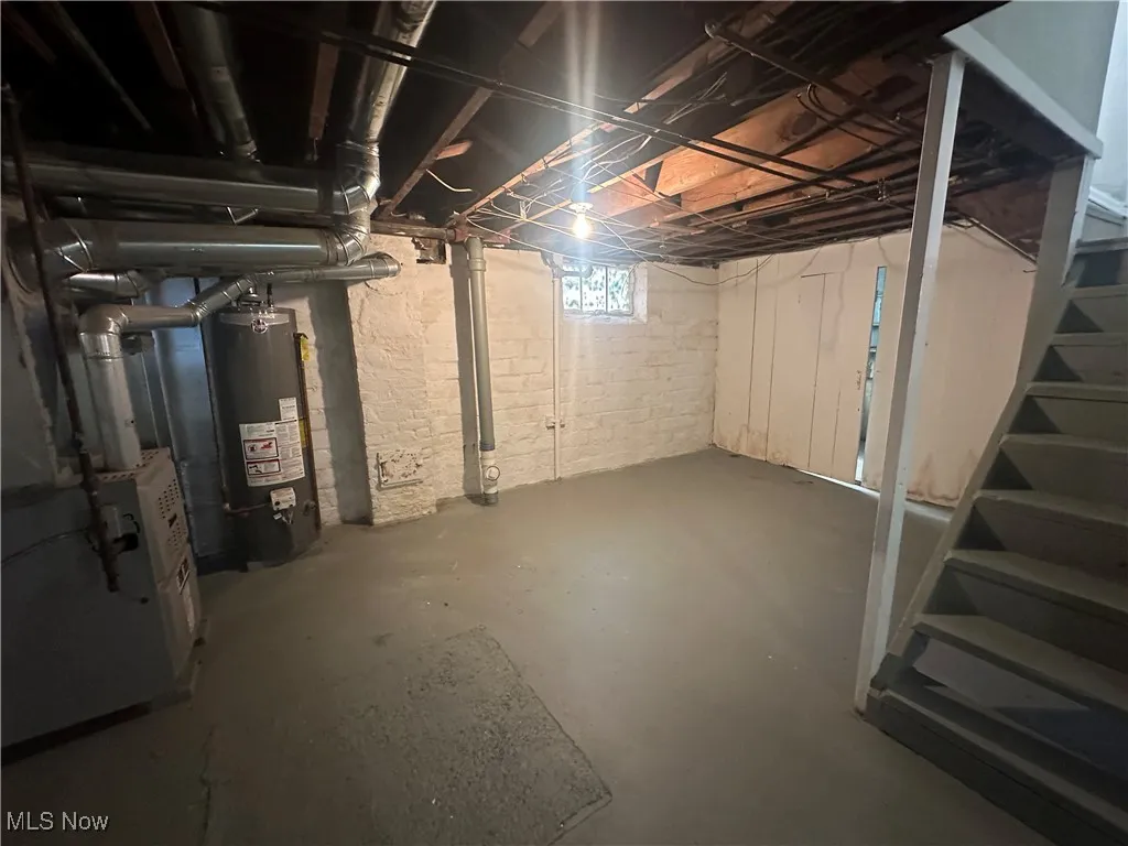 Below grade area with water heater, stairway, and heating unit