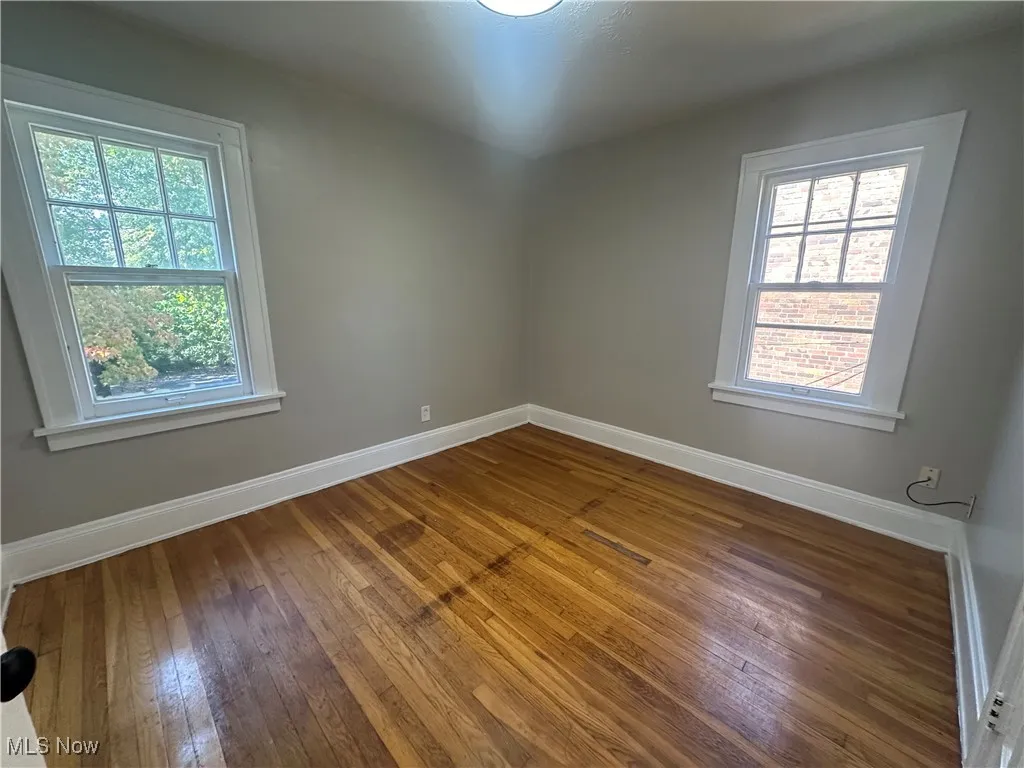 Empty room featuring baseboards and wood-type flooring