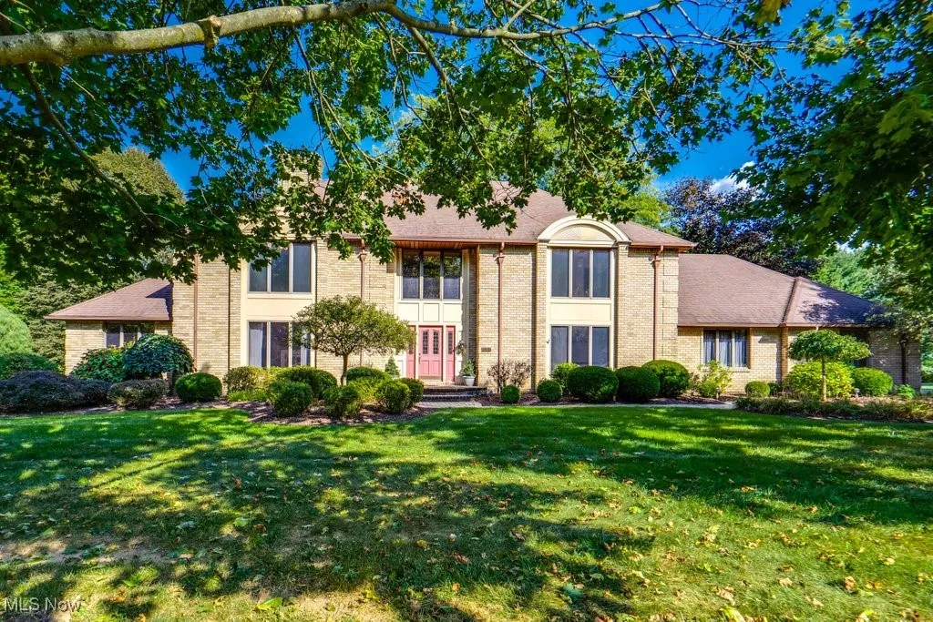 Traditional-style colonial hone featuring brick siding and a beautiful 1 acre lot and 3 garages.