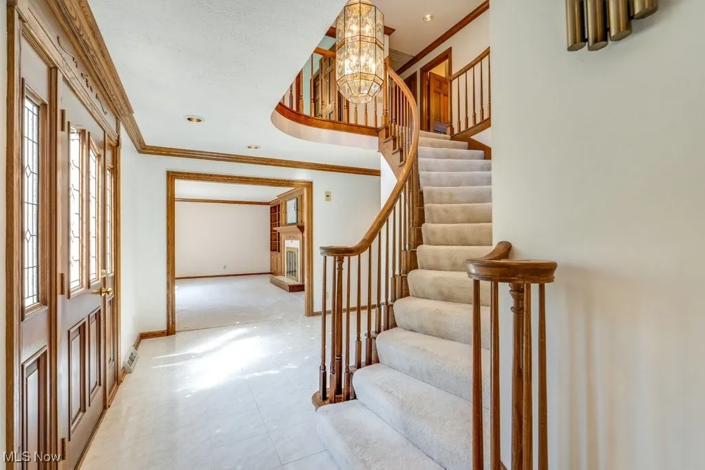 Stunning stairway and entrance with view to living area with fireplace.