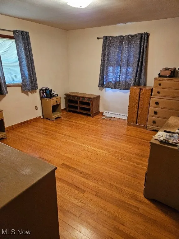 Bedroom with light wood-style flooring and a baseboard heating unit