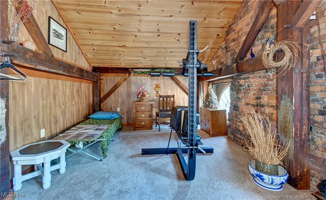 Exercise room with carpet flooring, high vaulted ceiling, wooden ceiling, and wood walls