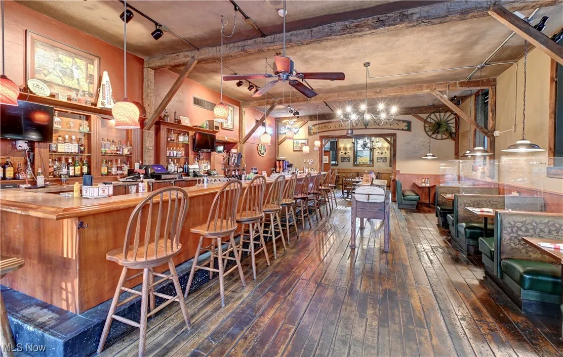 Community bar area with pendant lighting, dark wood-style floors, ceiling fan, and open shelves