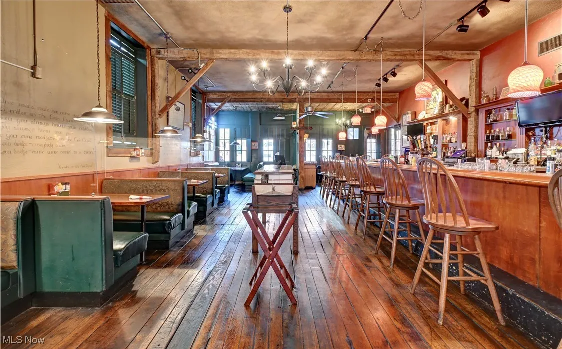 Dining space with dark wood-type flooring, wainscoting, a bar, and wooden walls