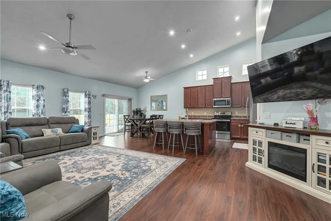 Living room featuring dark wood finished floors, high vaulted ceiling, a ceiling fan, and recessed lighting