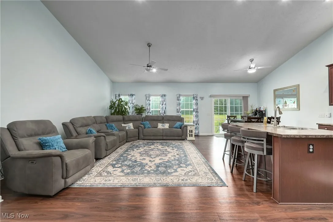 Living area with lofted ceiling, dark wood-style flooring, and ceiling fan