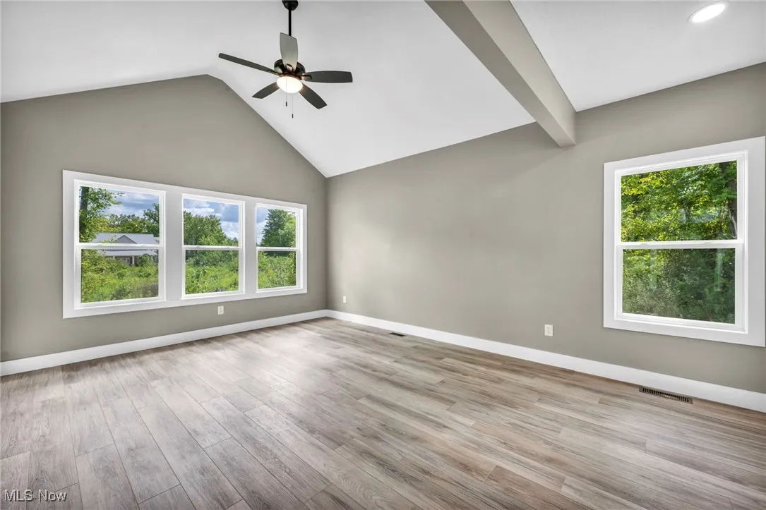 Spare room with light wood-style floors, ceiling fan, high vaulted ceiling, and beam ceiling