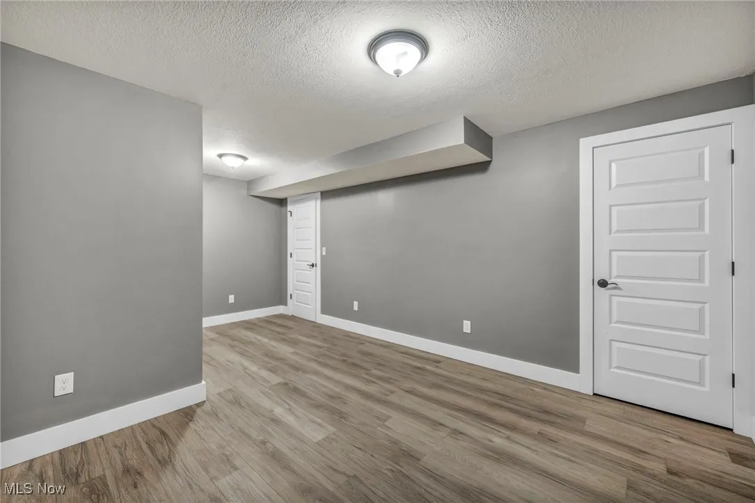 Finished below grade area featuring a textured ceiling and light wood-type flooring