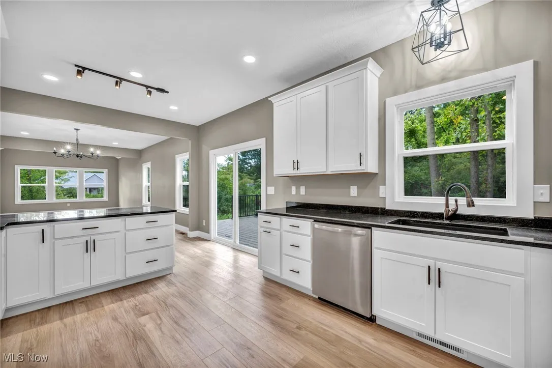Kitchen with pendant lighting, a chandelier, white cabinets, dishwasher, and plenty of natural light