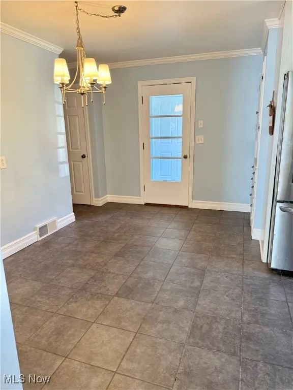 Unfurnished dining area with ornamental molding and a chandelier