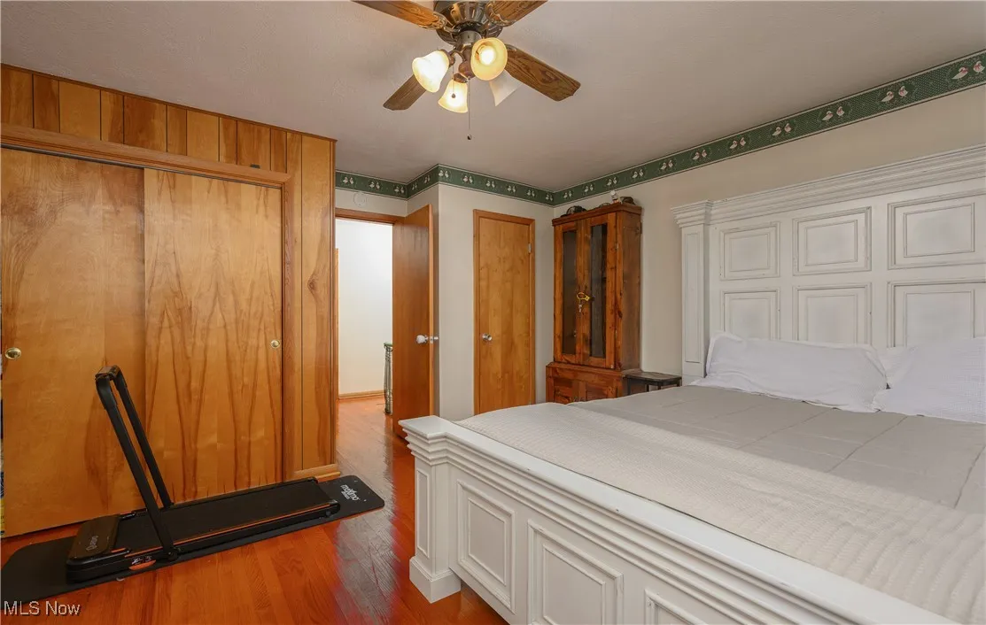 Bedroom featuring wood finished floors, ceiling fan, and two closets