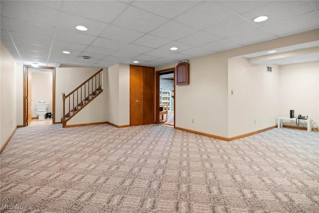 Finished basement with stairway, carpet, a drop ceiling, and recessed lighting